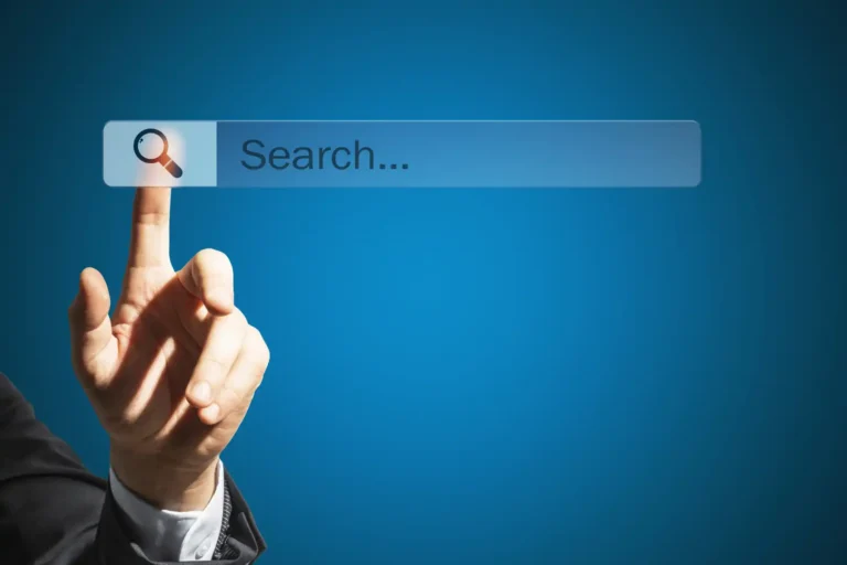 A person in a suit pointing a index finger at a translucent search bar with a magnifying glass icon on a blue background.